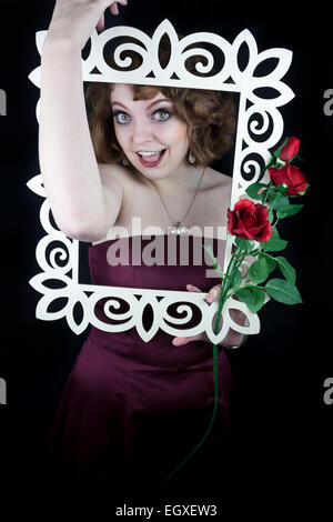 Schöne Frau mit weißen Holzrahmen mit roten Rosen mit ihren Armen Stockfoto