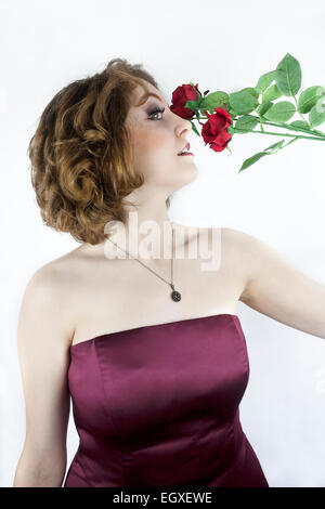 Schöne junge Frau tragen trägerlosen Kleid Satin mit roten Rosen. Stockfoto