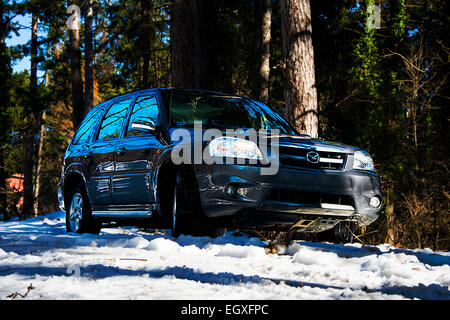 Rechten vorderen Seite des Mazda Tribute Sport Utiliy Fahrzeug auf der Bergstrasse im Schnee Stockfoto