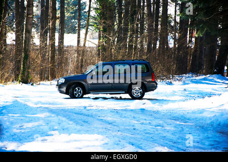 Linke Seite des Mazda Tribute Sport Utiliy Fahrzeugs auf der Bergstrasse im winter Stockfoto