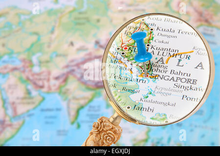 Blauen Stift auf der Weltkarte mit Lupe suchen in Singapur Stockfoto