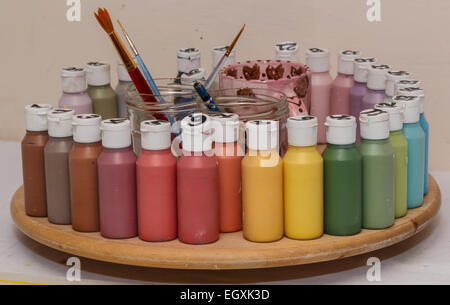 Gläser von keramische Farbe in vielen Farben auf einem hölzernen Spinner.  Bürsten und Wasserkrüge im Zentrum. Stockfoto