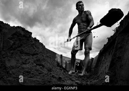 Ein kolumbianische Sand Bergmann entlädt den extrahierten Sand aus seinem Boot am Ufer des Flusses La Vieja in Cartago, Kolumbien. Stockfoto