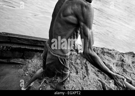 Ein kolumbianische Sand Bergmann entlädt den extrahierten Sand aus seinem Boot am Ufer des Flusses La Vieja in Cartago, Kolumbien. Stockfoto