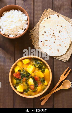 Overhead Schuss von Kürbis, Mangold, Kartoffeln und Tomaten curry-Gericht in Holzschale mit hausgemachten Chapati Fladenbrot Stockfoto