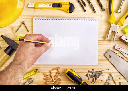 Planung eines Projekts in Zimmerei und Holzarbeiten Industrie, Notebook und verschiedene Holzarbeiten und Zimmerhandwerk-Werkzeuge auf Pinewood-Workshop Stockfoto