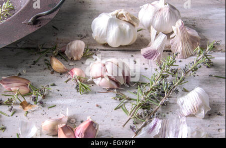 Knoblauch mit Rosmarin in einen alten rostigen Topf platziert auf einem weißen Bauernhaus Holztisch mit Platz für text Stockfoto