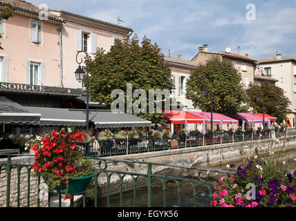 Die bunten Markisen an Straßencafés säumen den Rand des Flusses Sorgue im Herzen von L'Isle-Sur-la-Sorgue, Provence. Stockfoto