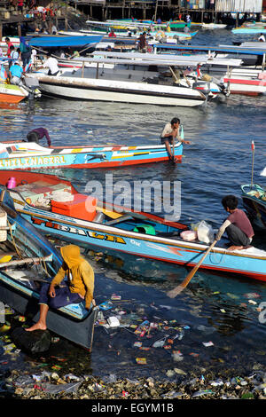 Hölzerne Taxiboote warten für die Passagiere auf der Uferpromenade, übersät mit Kunststoff-Flaschen und anderen Müll in Semporna, Borneo Stockfoto