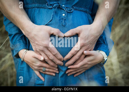 Hand des Menschen Herz auf den Bauch seiner schwangeren Freundin bilden Stockfoto