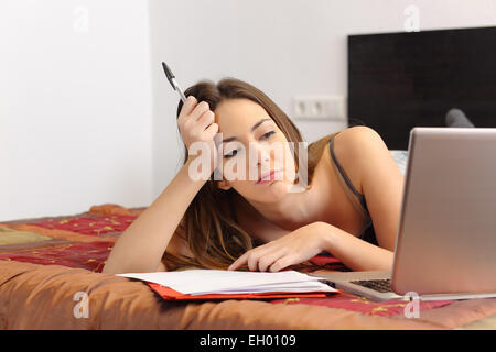 Gelangweilt studiert mit einem Laptop im Schlafzimmer zu Hause Stockfoto