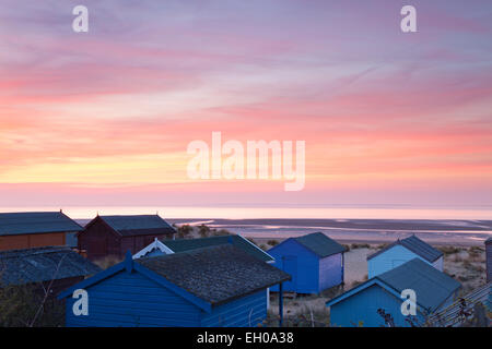 Blick auf einen Sonnenuntergang über der Wäsche von unter alten Hunstanton herrliche Sammlung von Strandhütten. North Norfolk, UK Stockfoto