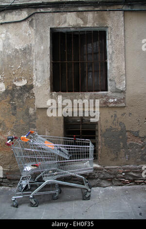 Alte Fenster mit Bars und verlassene Einkaufswagen in El Raval-Viertel im Zentrum von Barcelona, Katalonien Stockfoto