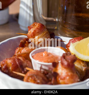 Tief gebratener Speck eingewickelt Jakobsmuscheln mit Fisch-Sauce und Zitrone in einem Straßencafé. Stockfoto