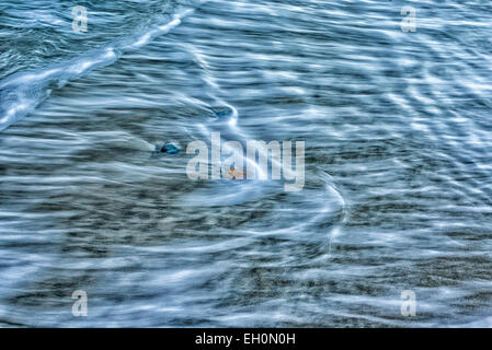 Wellen Waschen über kleine Felsen an einem Strand. Erweiterte Details und Kontrast. Stockfoto