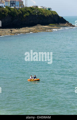 Kleinen Schlauchboot gepaddelt, zwei junge Männer ein Stück weit vor der Küste von Traeth Y Dolau Beach in New Quay, Ceredigion. Stockfoto