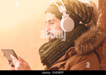 junger Mann hält einen Tabòet Notizblock mit seiner rechten Hand in eine städtische im Freieneinstellung Instagram Filte angewendet Stockfoto