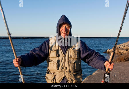 Alter Mann zeigt aufgeregt Angeln Rute und Net am Lake Ontario. Stockfoto