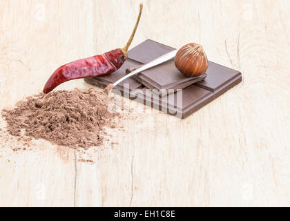 Vorderansicht von Chili Schokolade, Haselnüsse, Chili und überdachte Teelöffel Kakao. Stockfoto