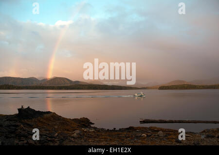 Eine kleine Fähre fährt unter einem Regenbogen im Pazifik des Great Bear Rainforest, in der Nähe von Bella, British Columbia, Kanada. Stockfoto