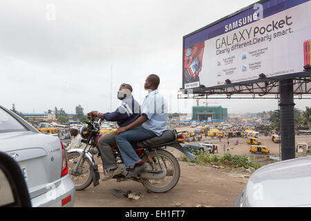 Lagos, Nigeria; Leute auf einem Motorrad in dichtem Verkehr. Stockfoto