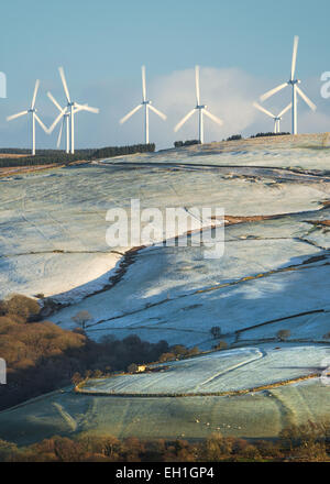 Ein Windpark auf landwirtschaftlichen Flächen in an einem frostigen Morgen in Süd-Wales, gibt es eine kleine Scheune nur unten. Stockfoto