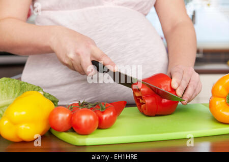 Schwangere Frau frisches Gemüse zerkleinern Stockfoto