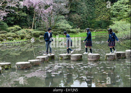 Schüler überqueren die Stufen über den See in den Gärten des Heian-Schreins (Heian Jingu), einem Shinto-Tempel in Kyoto, Japan Stockfoto