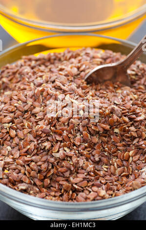 Eine Schüssel mit Bio Leinsamen und Leinöl im Hintergrund. Stockfoto