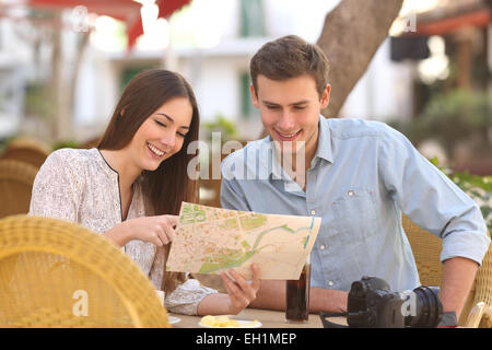 Glückliches Paar Touristen Beratung eine Anleitung in einer Restaurantterrasse Stockfoto