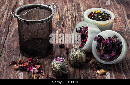 Teesieb und verschiedene Sorten von Tee Blätter auf hölzernen Hintergrund. Die getönten Bild Stockfoto