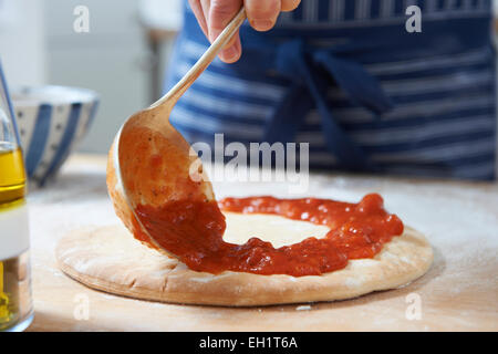 Nahaufnahme von Pizzateig Tomatensauce hinzufügen Stockfoto