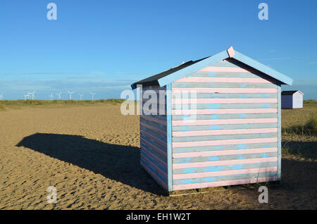 Strandhütten in der Nähe von Great Yarmouth - Windpark Scroby Sands im Hintergrund. 2014 Stockfoto