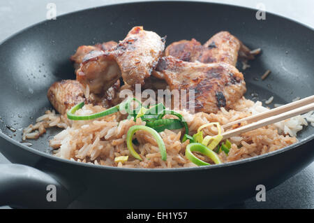 Reste. Gebratener Reis mit mit Soja-Sauce, Barbecue Chicken Wings und Lauch in einer Pfanne erhitzen. Stockfoto