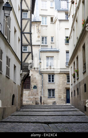 Ein Fachwerkbau ragt in einer engen, gepflasterten Straße im Marais Bezirk von Paris, Frankreich Stockfoto