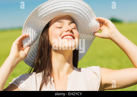 lächelnde junge Frau in Strohhut im freien Stockfoto