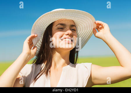 lächelnde junge Frau in Strohhut im freien Stockfoto