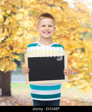 lächelnde Knabe hält leere schwarze Tafel Stockfoto