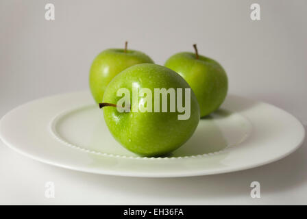 Drei grüne Granny Smith Apfel auf weißen Porzellanteller Stockfoto