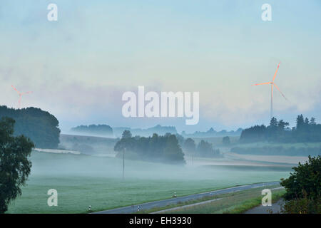 Malerische Aussicht auf nebligen Ackerland am Morgen mit Windrad im Hintergrund, Oberpfalz, Bayern, Deutschland Stockfoto