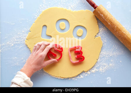 Obenliegende Ansicht von Frau Hand mit Ausstechformen lose in Rolled out Suger Plätzchenteig, Studio Shot buchstabieren Stockfoto