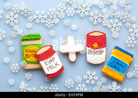 Obenliegende Ansicht von Zucker Cookies dekoriert wie Nahrungsmittel auf blauem Hintergrund mit Schneeflocken Stockfoto
