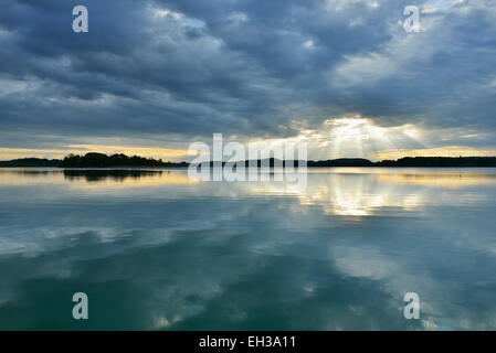 Wolken und dämmerungsaktiv Sonnenstrahlen zeigen im See bei Sonnenaufgang, Woerthsee See, Oberbayern, Fuenfseenland, Deutschland Stockfoto