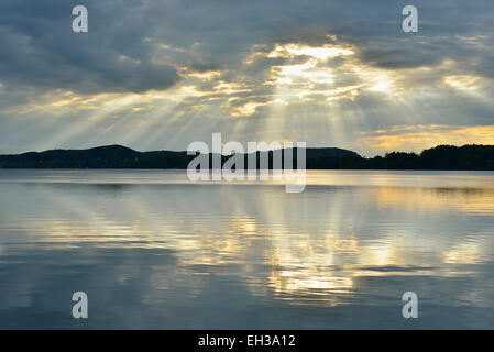Wolken und dämmerungsaktiv Sonnenstrahlen zeigen im See bei Sonnenaufgang, Woerthsee See, Oberbayern, Fuenfseenland, Deutschland Stockfoto