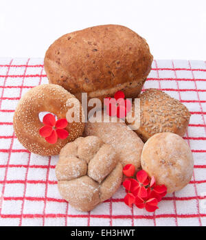 Ein Getreidespeicher Brot und verschiedene Brötchen mit roten Blüten auf einem roten und weißen Tuch. Stockfoto