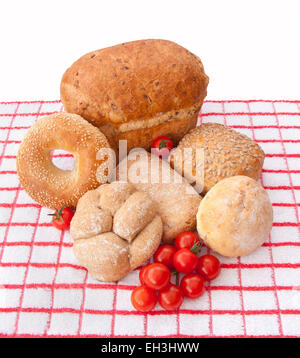 Kornkammer Laib und verschiedene Brot Brötchen und Cherry-Tomaten auf einem roten und weißen Tuch. Stockfoto