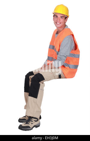 Junge Handwerker sitzen auf einem unsichtbaren block Stockfoto