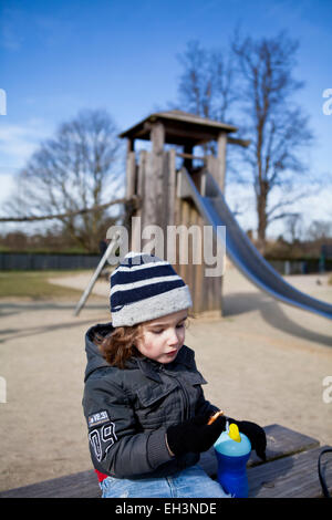 Kleinkind Essen auf einem Spielplatz Stockfoto