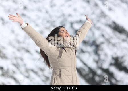 Glückliche Frau anheben Arme auf Winterurlaub mit einem schneebedeckten Berg im Hintergrund Stockfoto