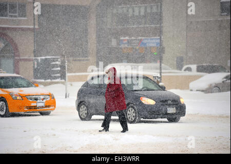 Eine Frau kreuzt eine Straße in Kanada als Schnee fällt. Stockfoto